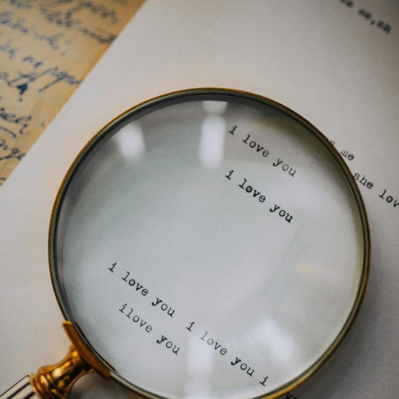 Close-up of a magnifying glass highlighting 'I love you' on a letter, capturing romantic sentiment.